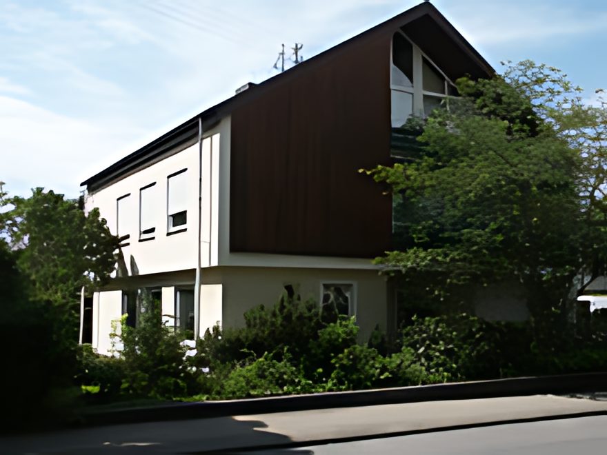 Wohnhaus vor der Fassadenrenovierung: verwitterte weiße Fassade mit dunkler Holzverschalung