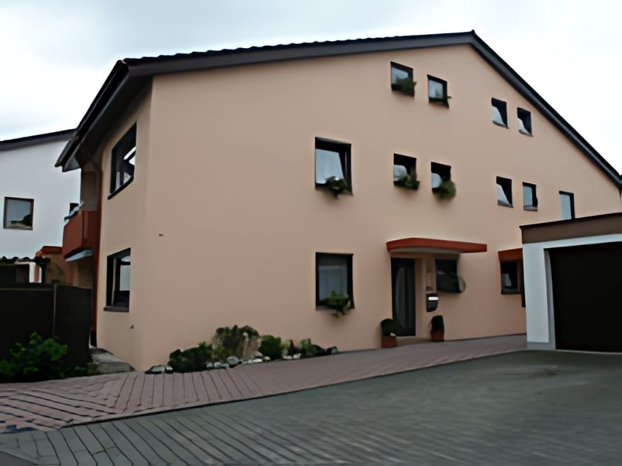 Renovierte Hausfassade in warmem Apricot mit gestalteten Fensterrahmen